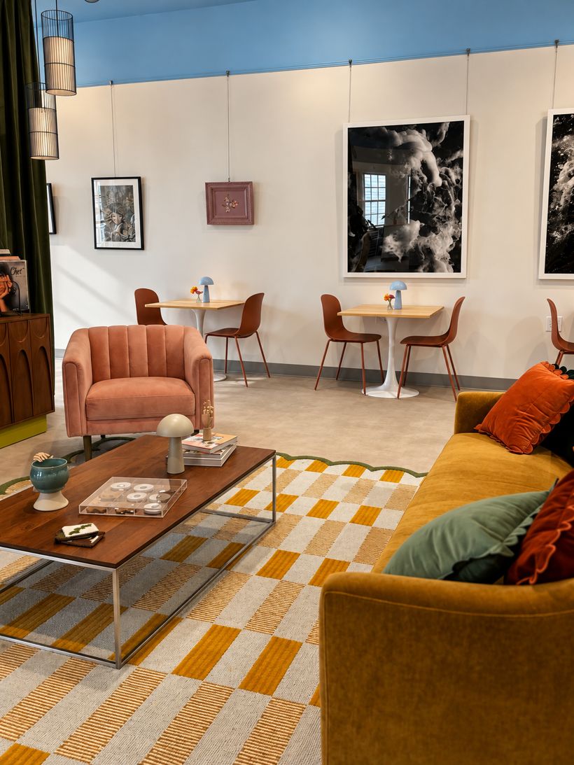 The Atelier lounge: a pink velvet armchair, mustard sofa and checkered rug beneath gallery walls